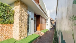 A narrow pathway leading to a building with ornate columns and a stone wall. - Mahesa Home Seminyak (Seminyak)