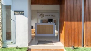 A reception area with a wooden reception desk and a sign for Mahesa Suites. - Mahesa Home Seminyak (Seminyak)