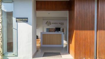 A reception area with a wooden reception desk and a sign for Mahesa Suites.