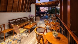 An outdoor seating area with wooden furniture, including benches and tables, arranged under a wooden pergola. - Mahesa Home Seminyak (Seminyak)