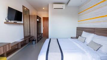 A modern hotel room with a large bed, a flat-screen TV mounted on the wall, a wooden wardrobe, and a built-in bench.