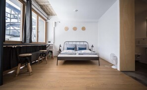 Ein modernes Schlafzimmer mit einem Bett, Holzschemeln, einem Fenster und einer Heizung.