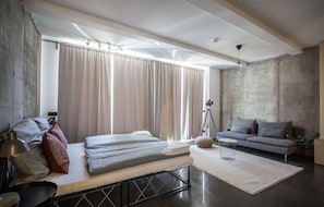 A modern bedroom with a bed, a sofa, and a large window with curtains. - Nena Apartments Metropol Park Berlin - Mitte (Berlin)