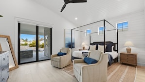 Ein Schlafzimmer mit Himmelbett, zwei Sesseln, einem Nachttisch und einem großen Fenster mit Blick ins Freie.