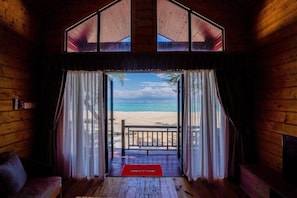 Una baita di legno con un balcone e vista sulla spiaggia.