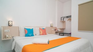 A hotel room with a bed, pillows, a bedside table, a phone, and a towel. - Sans Hotel Fiffa Premiere Malang (Malang)