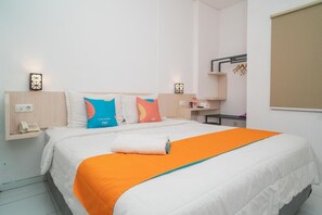 A hotel room with a bed, pillows, a bedside table, a phone, and a towel. - Sans Hotel Fiffa Premiere Malang (Malang)