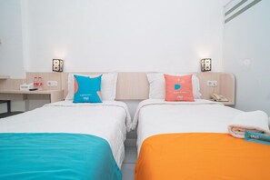A hotel room with two beds, each with a different colored bedspread. There are two bedside tables, one on each bed, with a lamp on each. The room has a simple, clean design with white walls and a wooden headboard. - Sans Hotel Fiffa Premiere Malang (Malang)