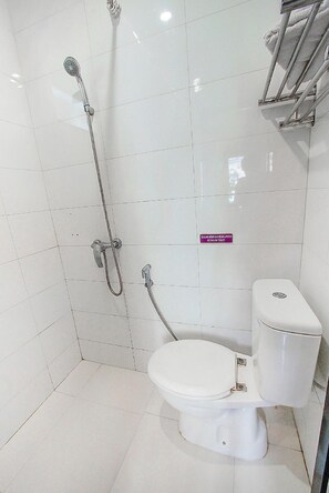 Un baño con inodoro blanco, ducha con cabezal de ducha manual y un letrero que indica que el inodoro es para hombres.