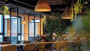 A restaurant interior with tables and chairs, hanging lamps, and large windows. - Hotel Alice and Trunk (Jeju City)