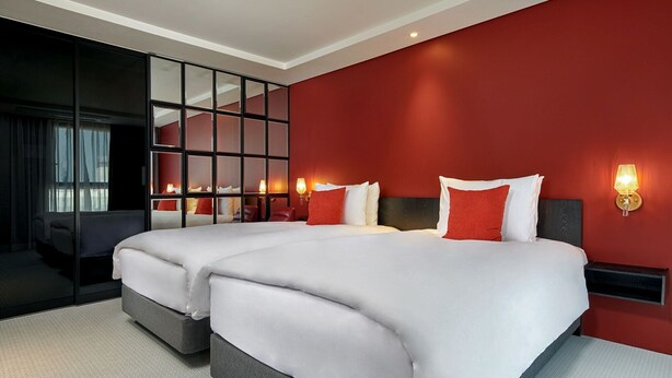 A hotel room with two beds, a large mirror, and a red accent wall. - Hotel Alice and Trunk (Jeju City)
