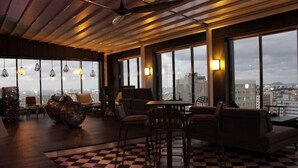 A modern lounge area with a checkered floor, large windows offering city views, and contemporary furniture. - Hotel Alice and Trunk (Jeju City)