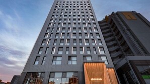 A modern high-rise building with a prominent restaurant on the ground floor. - Hotel Alice and Trunk (Jeju City)