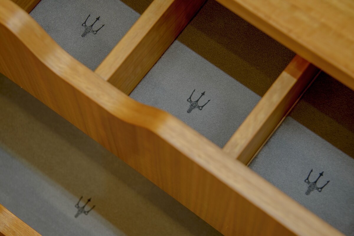 A wooden drawer with multiple compartments, each containing a small, identical object.