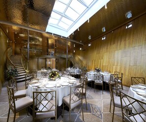 Un vaste espace dédié à la salle à manger, avec des tables rondes, des chaises et un escalier central.