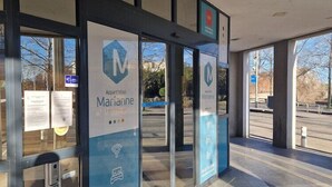 Entrada moderna de un hotel con puertas de vidrio, un cartel que dice 'Apartmenthotel Marianne' y un número de contacto.