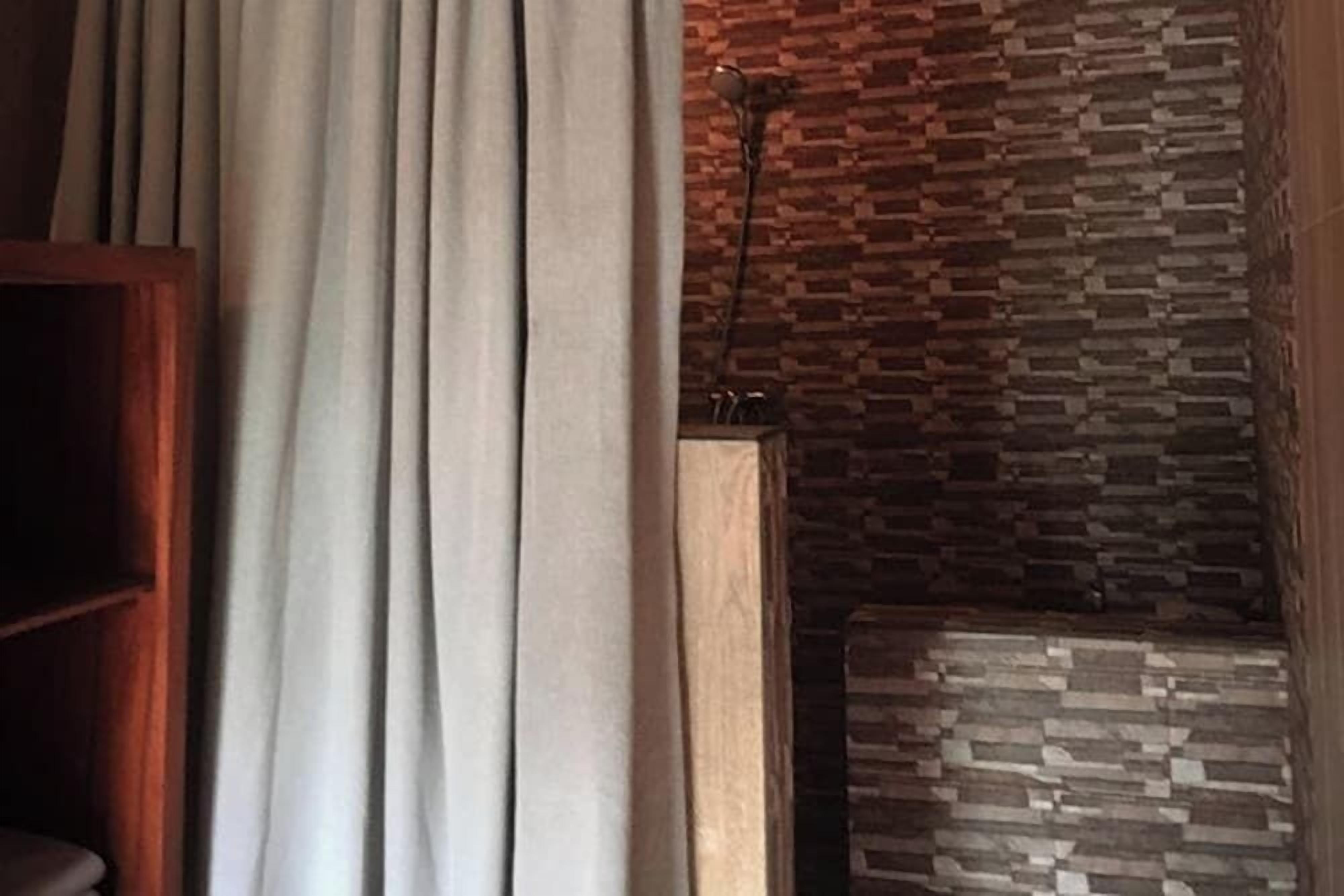 A room with a wooden cabinet, a patterned wall, and a curtain.