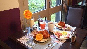 Ein Frühstückstisch mit Croissants, Orangenschnitten, Eiern, Schinken und Saft.