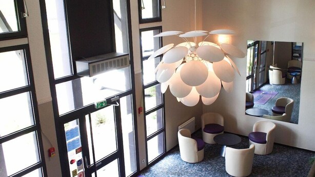Ein modernes Interieur mit großen Fenstern, einer einzigartigen, kugelförmigen Leuchte und einer Spiegelwand, die den Raum reflektiert.