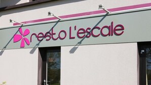 Ein Gebäude mit einem Schild, das "resto L'escalle" zeigt, und einem rosa Blütenlogo.