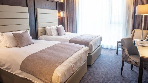 Une chambre d’hôtel avec deux lits, un bureau et une chaise.