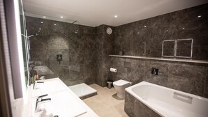 Une salle de bain moderne dotée d’une grande baignoire, d’une douche séparée et d’un meuble-lavabo avec un miroir.