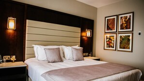 Une chambre d’hôtel avec un grand lit, deux tables de chevet et des appliques murales.