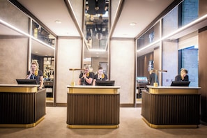 A hotel reception area with three reception desks, a central corridor, and a large window on the right. - Crow Wood Hotel and Spa Resort (Burnley)