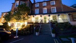 A two-story building with a brick facade, a central entrance with a staircase, and a small balcony with hanging flower baskets. - Brandshatch Place Hotel and Spa (Longfield)
