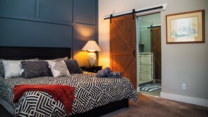 A bedroom with a bed, a nightstand, a lamp, a sliding glass door, and a framed picture on the wall. - Modern Oasis in Heart of Fountain Square, 4BR/3BA (Indianapolis)