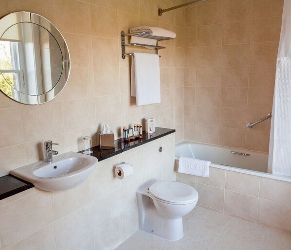A modern bathroom with a round mirror, a sink, a toilet, and a bathtub. - Classic Lodges Farington Lodge (Leyland)