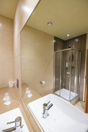 A modern bathroom with a large bathtub, a glass-enclosed shower, and a toilet paper dispenser. - Classic Lodges Farington Lodge (Leyland)