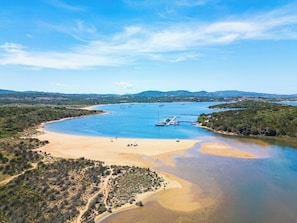 A coastal landscape with a sandy beach, a marina with boats, and distant hills. - Residence Costa Serena (Palau)