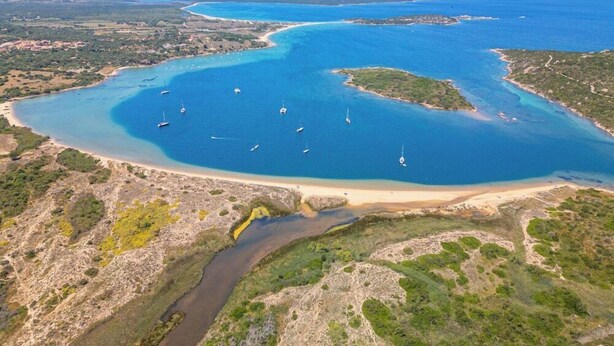 An aerial view of a coastal area with clear blue waters, boats, and a sandy beach. - Residence Costa Serena (Palau)