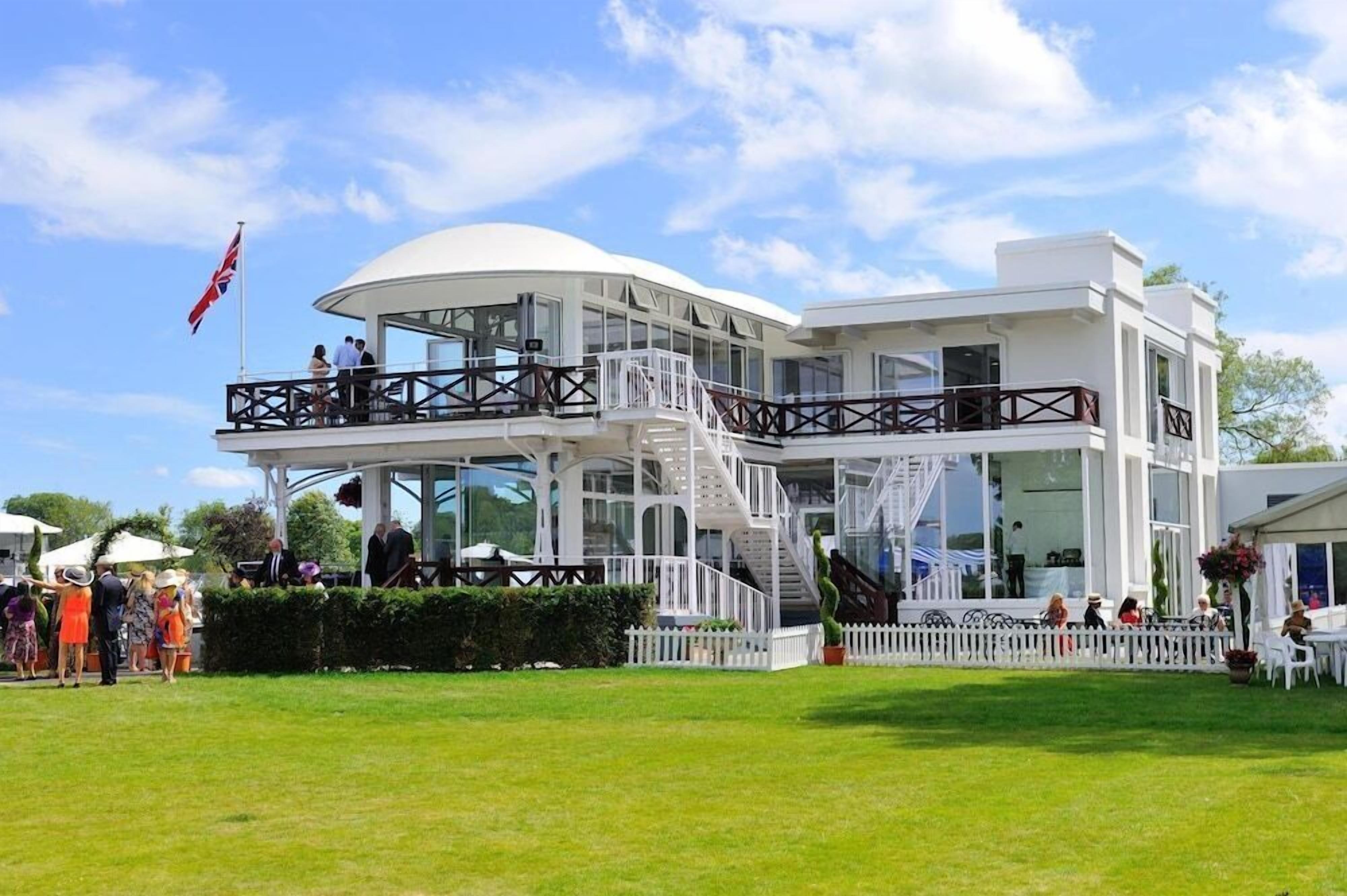 A modern two-story building with a white exterior, large windows, and a covered outdoor area with a white picket fence.