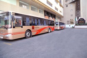 Deux autobus sont stationnés devant un immeuble sur lequel on peut lire les inscriptions « Hôtel » et « Services aux clients ».