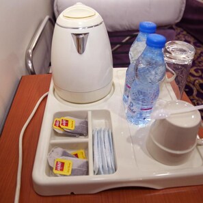 A hotel room tray with a kettle, water bottles, tea packets, and a cup. - Amjad Al Deafah (Makkah)