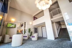 Un vestíbulo moderno con una escalera, zonas de estar y una pantalla de televisión.