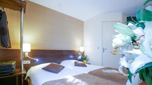 A hotel room with a bed, bedside lamps, a coat rack, and a potted plant. - Hotel Inn Design Langres Resto Novo (Langres)