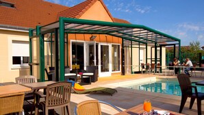 A covered outdoor seating area with a pool, dining tables, and chairs. - Jum Hotel - Auberge Des 3 Jumeaux (Saints-Geosmes)