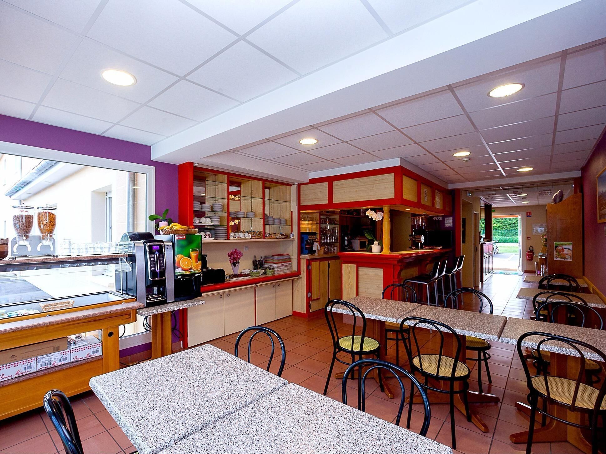 A restaurant interior with a counter, seating area, and a display of food items.