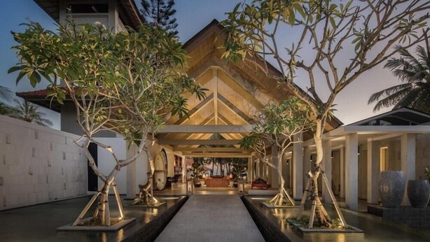 A modern building with a central atrium, surrounded by trees and a pathway leading to the entrance. - Umadewi Surf and Suites (Pekutatan)