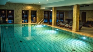 An indoor swimming pool with tiled walls, lounge chairs, and a clear pool. - 4moods Suites and Spa Erwachsenenhotel (Bad Griesbach im Rottal)