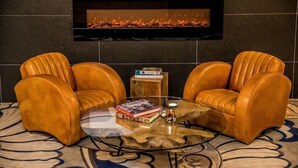 A room with two leather armchairs, a glass coffee table, and a fireplace. - 4moods Suites and Spa Erwachsenenhotel (Bad Griesbach im Rottal)