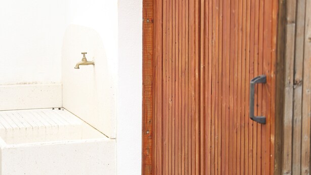 Une baignoire blanche avec un robinet, une porte en bois avec une poignée et un mur recouvert de panneaux en bois.