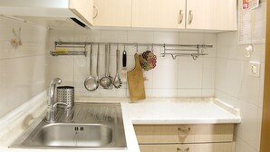 Une cuisine dotée d’un évier en acier inoxydable, de meubles en bois et d’une variété d’ustensiles de cuisine suspendus à un porte-ustensiles.