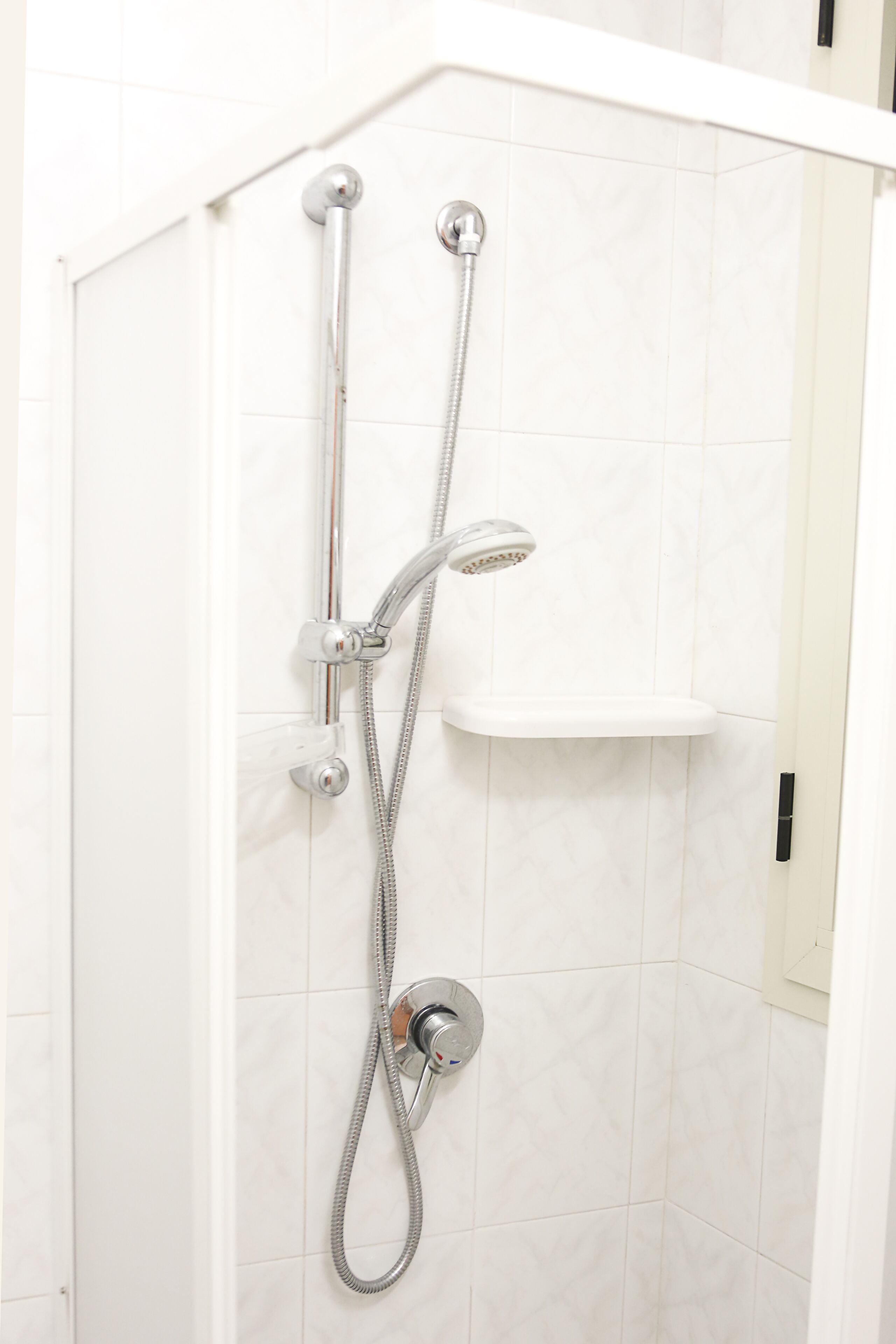 Une douche équipée d’un pommeau de douche à main et d’un pommeau de douche fixe fixé au mur.