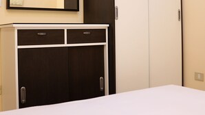 Une chambre à coucher avec un lit, une armoire, un miroir et un petit meuble.