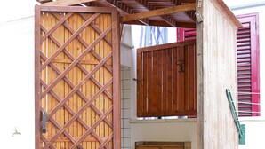 Une structure en bois dotée d’une porte à treillis, d’une petite étagère en bois et d’un loquet en métal.