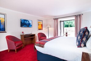 A hotel room with a bed, a desk, two chairs, a TV, and a window with curtains. - Parkway Hotel and Spa (Cwmbran)